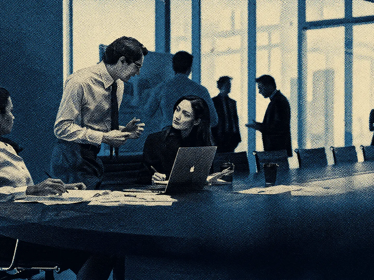 An engagement team at a boardroom table, working through papers and a laptop while a colleague talks them through a schedule